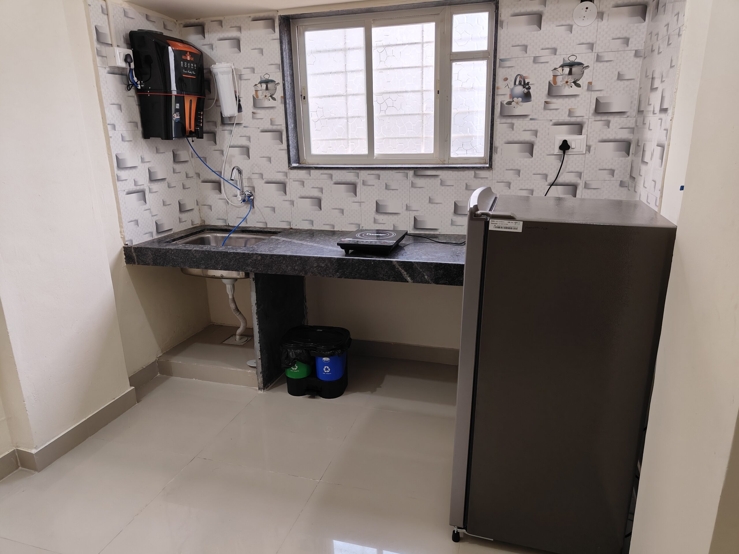 Fully equipped kitchen with induction cooktop, refrigerator and storage in Hinjewadi